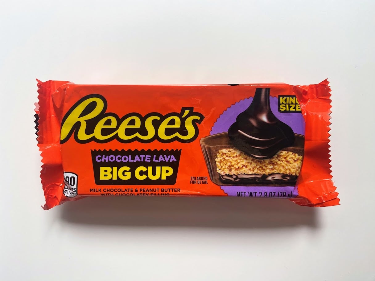 A wrapped package of Reese’s Chocolate Lava Big Cup candy, featuring an image of a chocolate peanut butter cup filled with chocolate lava and labeled "King Size." The packaging is predominantly orange and brown.