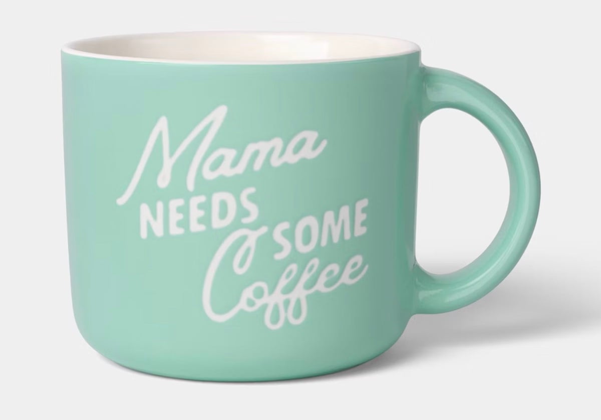 A light teal coffee mug with the phrase "Mama needs some coffee" written in white cursive and print lettering on the side—perfect for thoughtful Mother's Day gifts.