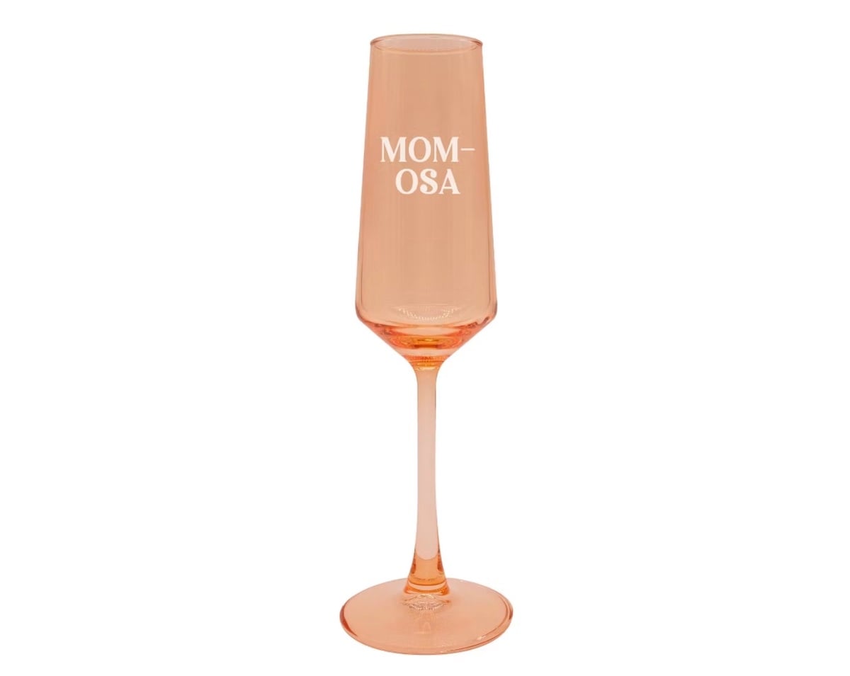 A peach-colored champagne flute with the word "MOM-OSA" printed in white letters on the glass—perfect for unique Mother's Day gifts.