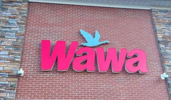The Wawa store logo in large red letters with a light blue flying bird above it, displayed on a brick wall with stone accents on the left side, was seen shortly after news of recent Wawa Recalls Beverages surfaced.