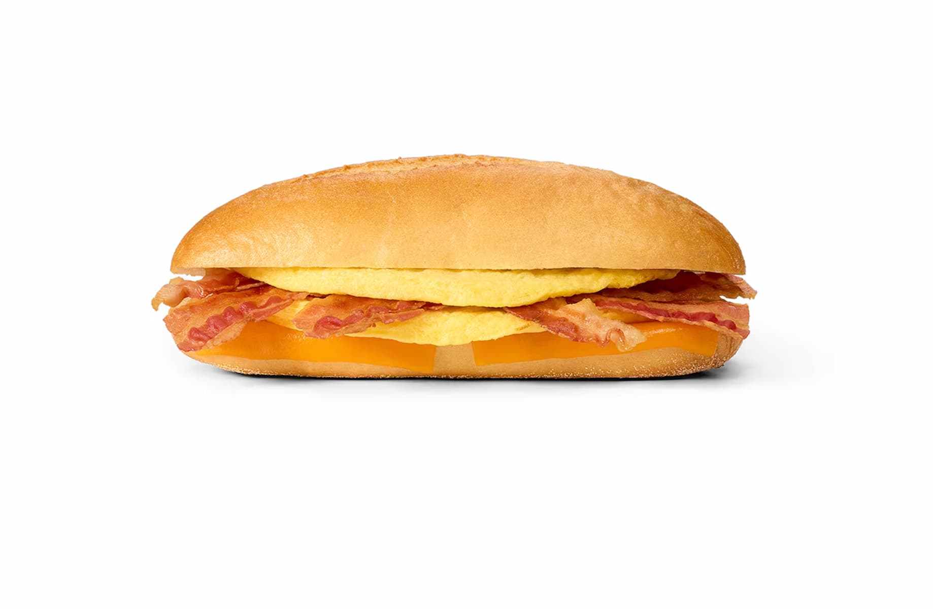 A breakfast sandwich with bacon, egg, and cheddar cheese in a golden, oval-shaped bun, shown on a white background.