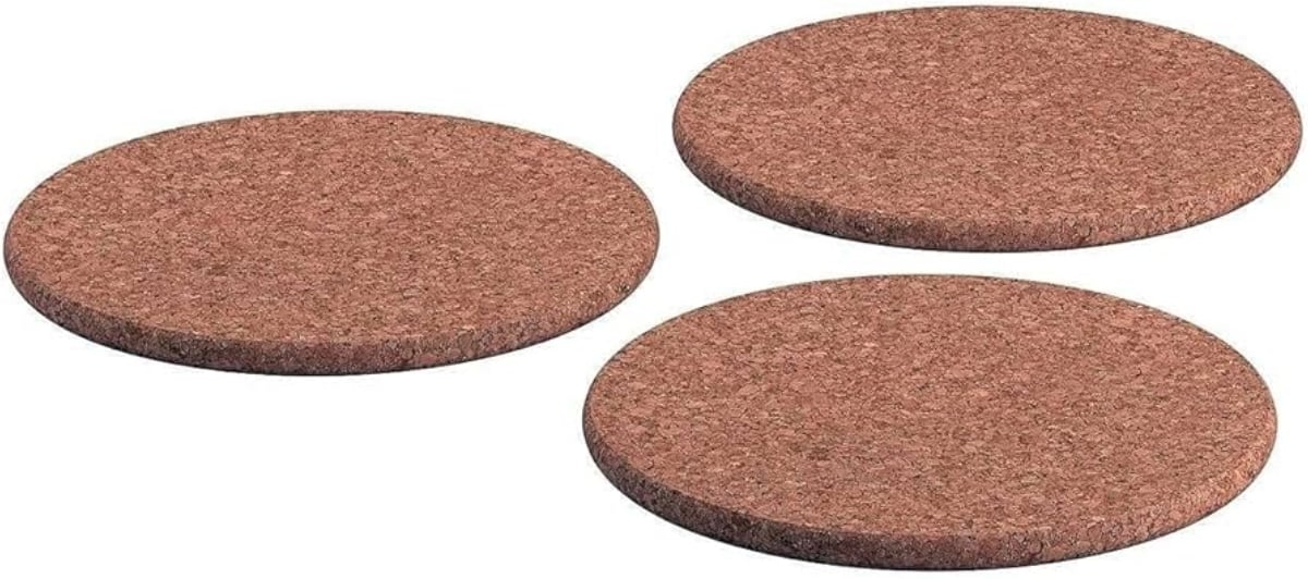 Three round brown cork coasters are placed on a white background, evenly spaced and laying flat.