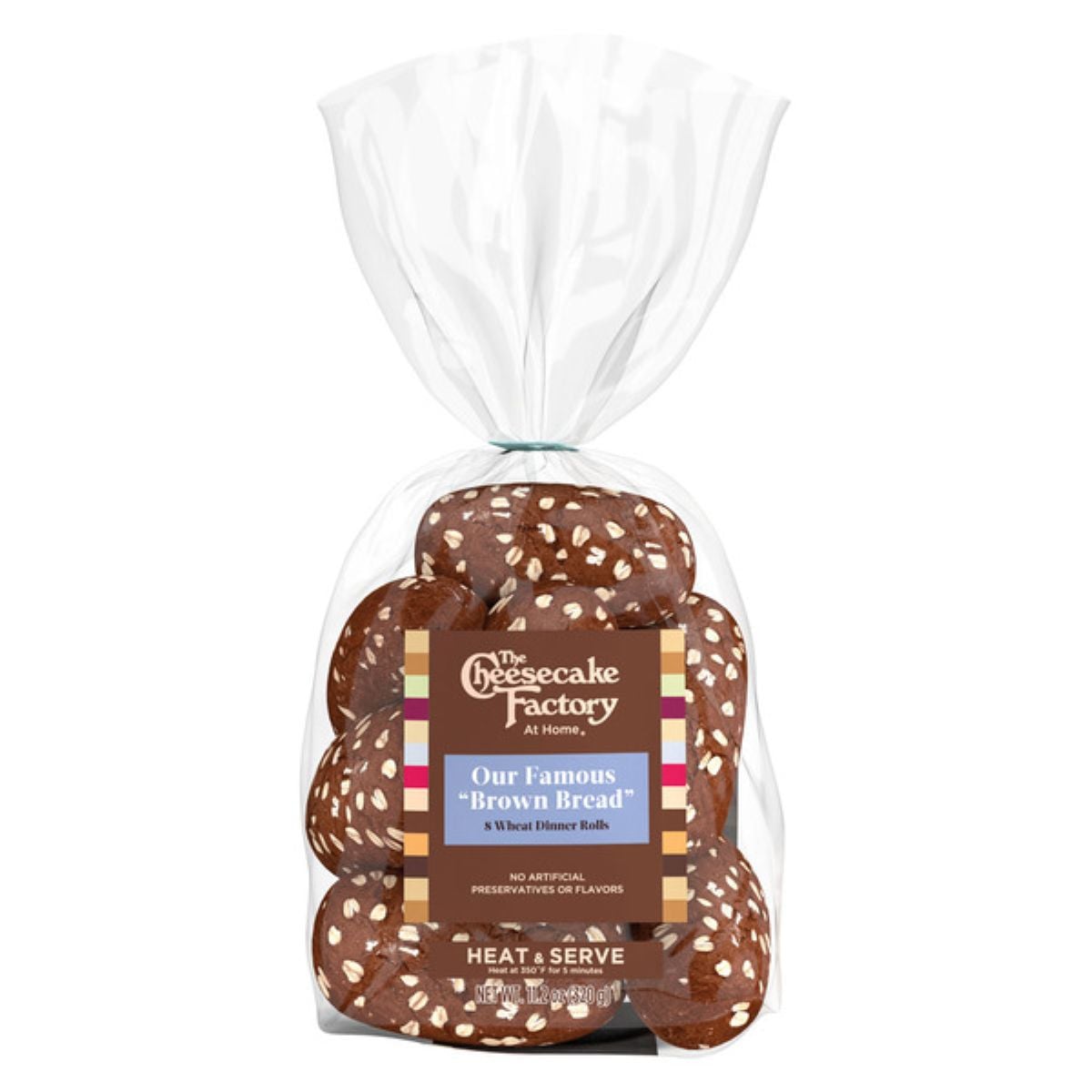 A clear plastic bag containing The Cheesecake Factory At Home's "Brown Bread" wheat dinner rolls, topped with oats. The label highlights they are famous rolls with no artificial preservatives or flavors.