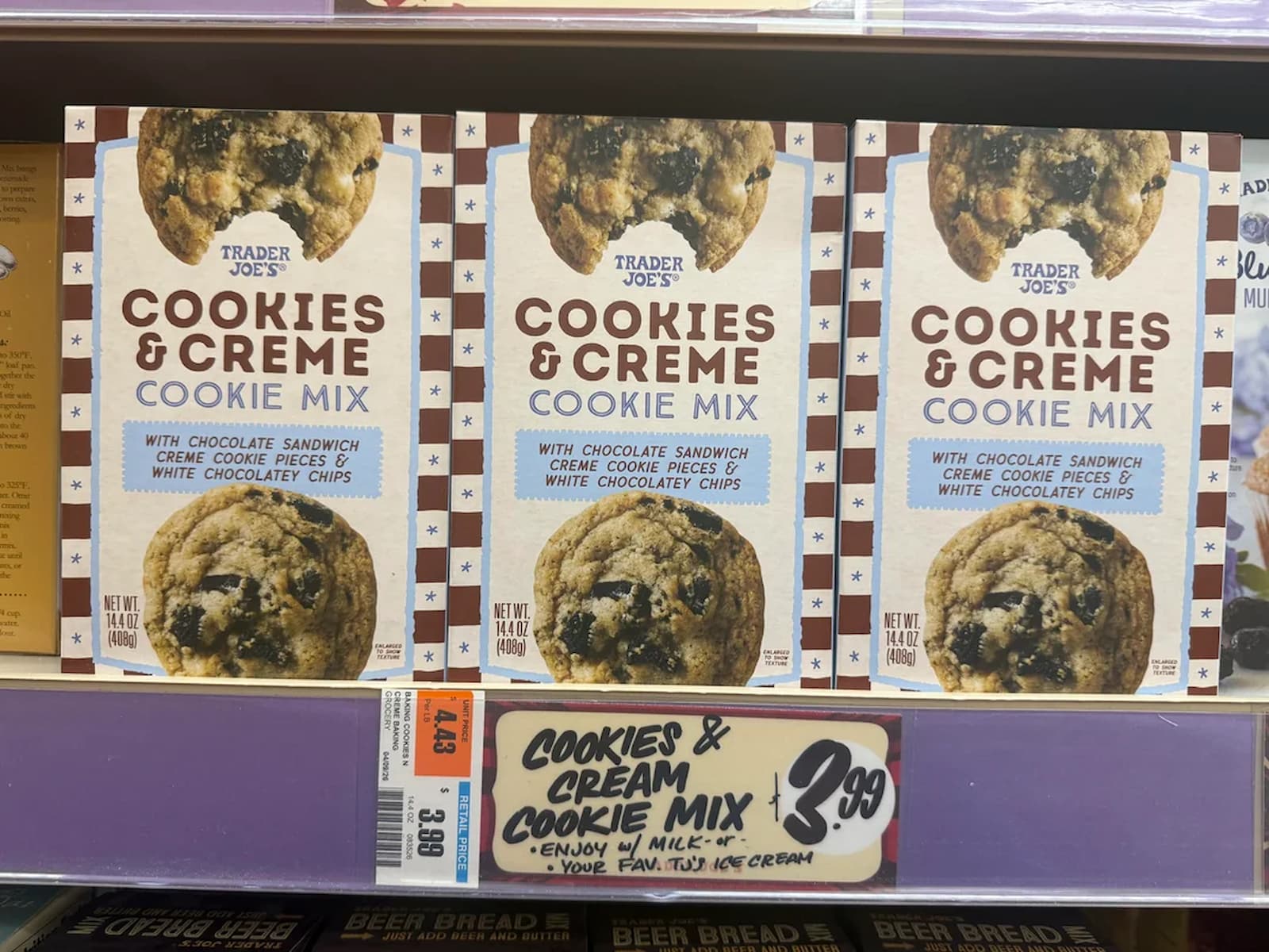 Three boxes of Trader Joe’s Cookies & Creme Cookie Mix are displayed on a store shelf. The packaging features a large cookie image and describes the mix as containing chocolate sandwich cookie pieces with white chocolate chips.