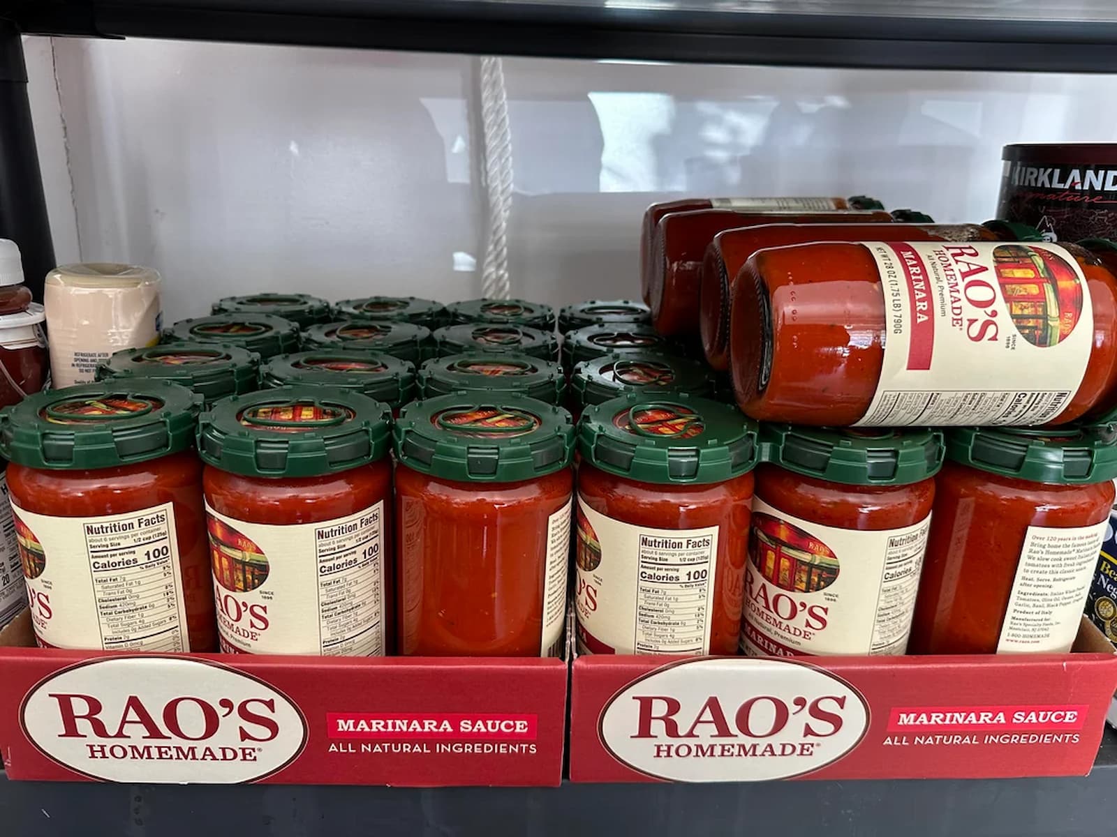 Several jars of Rao’s Homemade Marinara Sauce are displayed on a shelf, with most jars standing upright and some lying on their side. The labels are visible, showing the brand and product name.