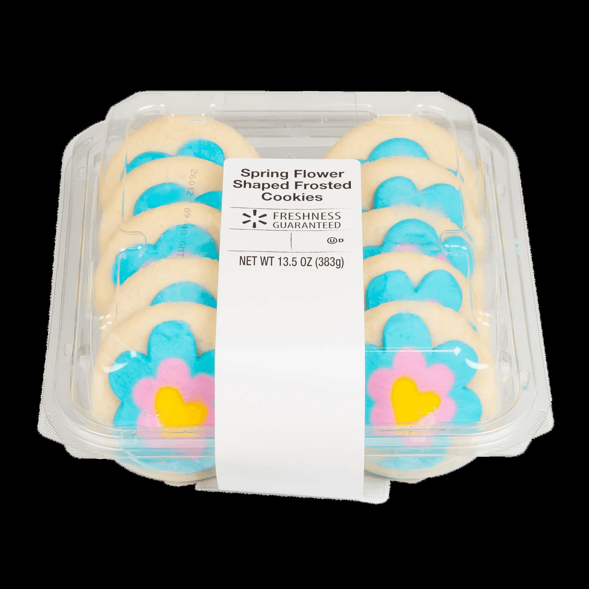 A clear plastic container holds frosted sugar cookies shaped like flowers, decorated with blue and pink icing petals and yellow centers. A white label on top reads “Spring Flower Shaped Frosted Cookies.”