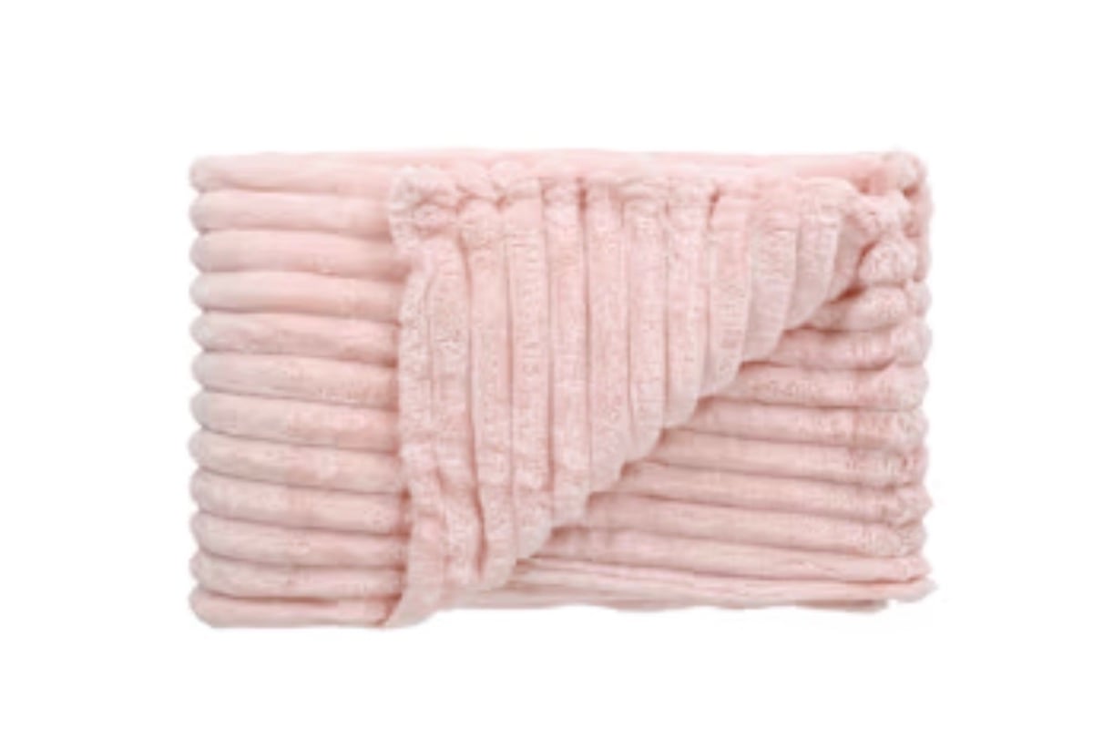 A folded, ribbed pale pink blanket from Five Below with one corner flipped over reveals its plush, soft texture. The blanket is neatly arranged on a white background.