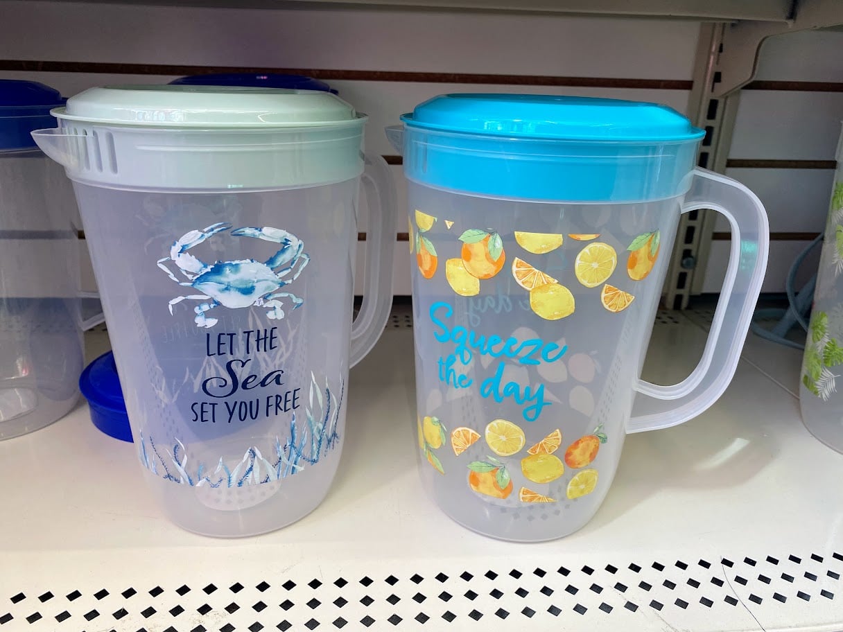 Two clear plastic pitchers on a store shelf; the left one has a blue crab and sea motif with the text "LET THE SEA SET YOU FREE," and the right one features lemon slices and the text "Squeeze the day.