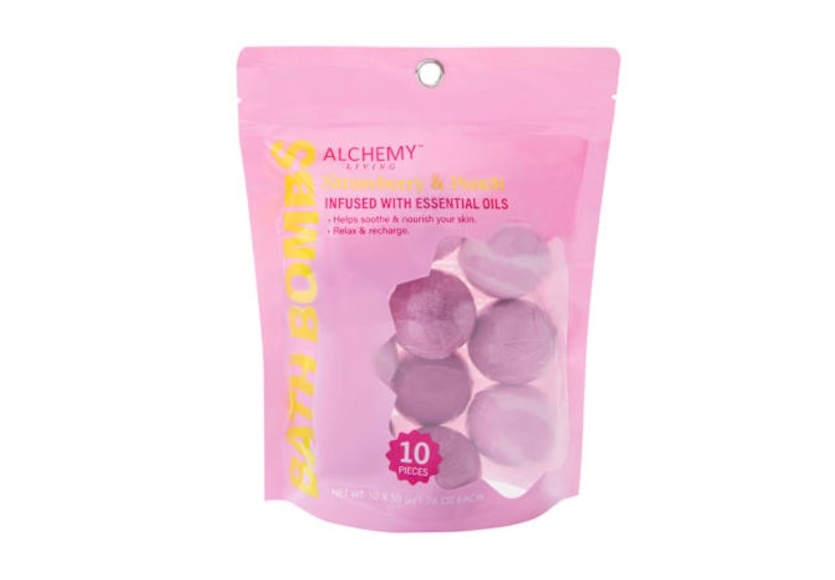 A pink resealable pouch labeled "Alchemy Living Strawberry & Peach Bath Bombs" from five below contains ten round bath bombs, highlighting their essential oil infusion to soothe and nourish skin.