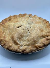 A golden-brown pie with a flaky, crimped crust and small slits cut into the top, sitting in a metal pie pan against a plain white background.