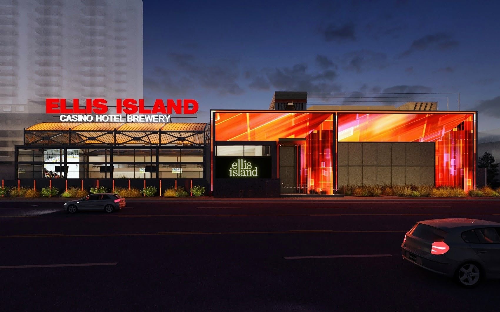A nighttime view of Ellis Island Casino Hotel Brewery in Las Vegas, a favorite for Las Vegas budget tips, with bright red and orange illuminated panels on the building and cars parked on the street in front.
