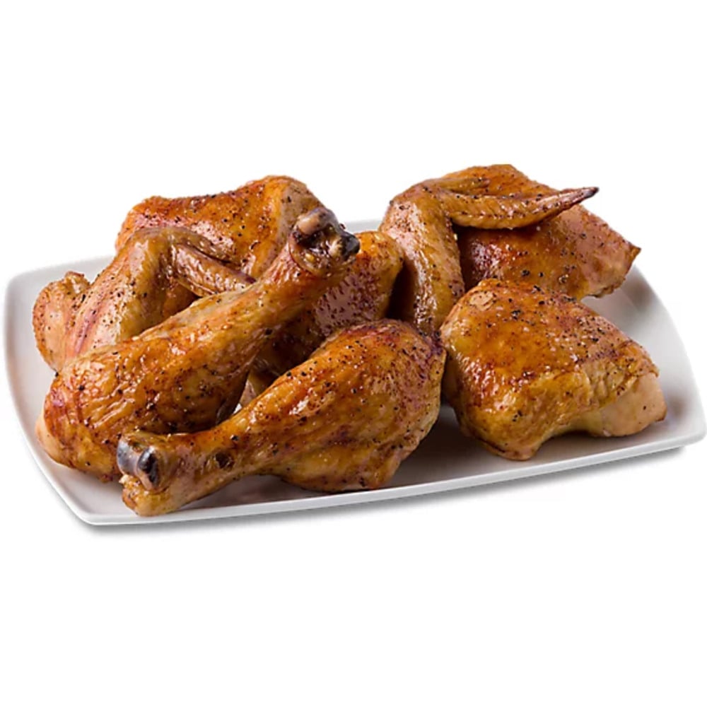 A rectangular white plate with several pieces of seasoned, roasted rotisserie chicken, including drumsticks and wings, arranged on it.