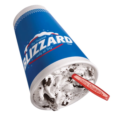 A Dairy Queen Blizzard treat in a blue cup, filled with cookies and cream ice cream, is tipped on its side with a red spoon sticking out—a classic choice among fast-food desserts.