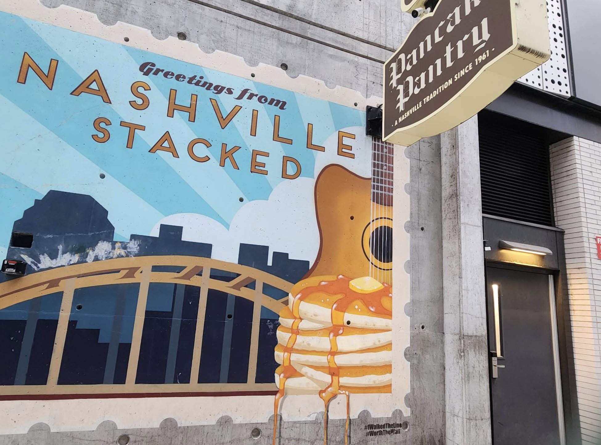 A mural shows "Greetings from Nashville Stacked" with a city skyline, a guitar, and a stack of pancakes with syrup. The Pancake Pantry sign hangs above a door on the building's exterior.