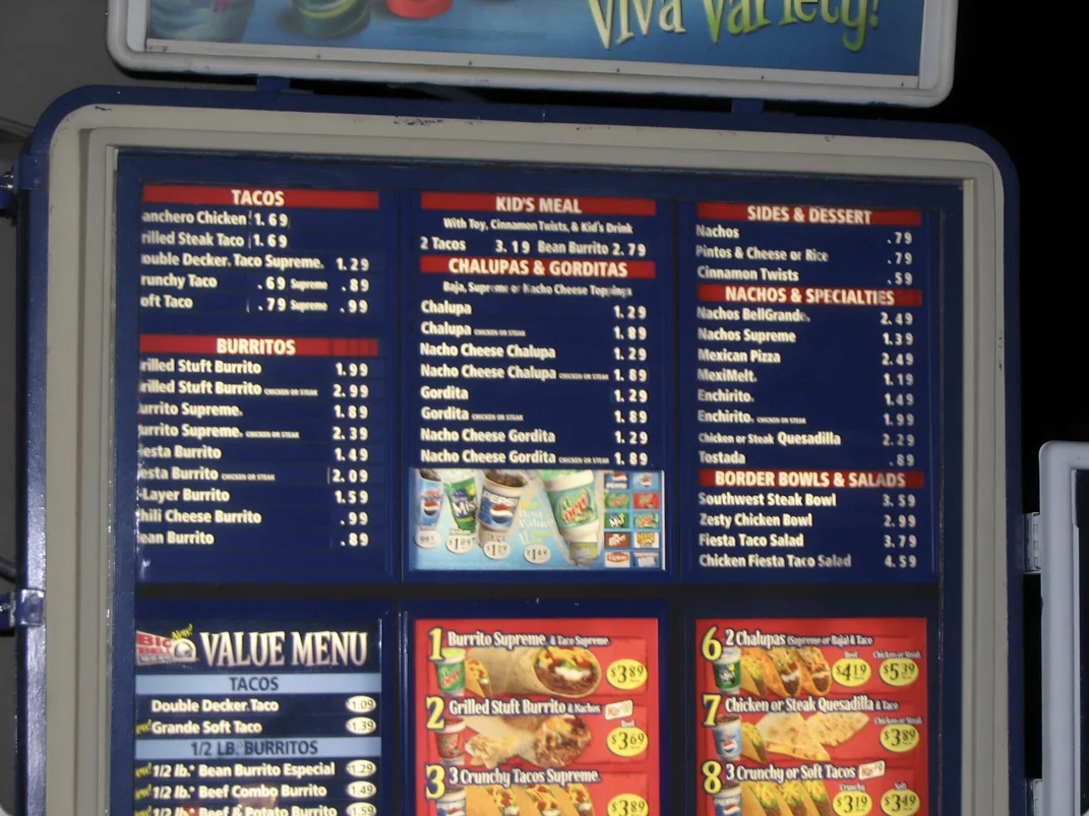 A vintage fast-food menu board displays various items including tacos, burritos, kid’s meals, chalupas, gorditas, nachos, sides, desserts, border bowls, and a value menu with prices. Perfect for fans of Vintage Fast-Food Photos.