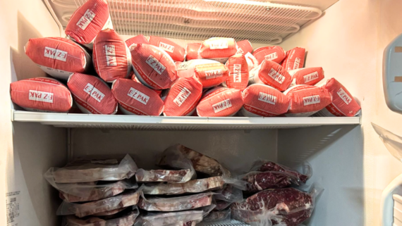 A freezer packed with red and white-labeled meat packages on the top shelf and vacuum-sealed cuts below&mdash;once cheap foods that are expensive now, these different types of meat are neatly organized by shelf in the full freezer.