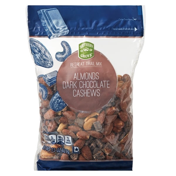 A clear bag of Southern Grove Retreat Trail Mix labeled "Almonds Dark Chocolate Cashews," showing mixed nuts and chocolate pieces inside. The bag weighs 15 ounces and features blue illustrations of nuts on the packaging.