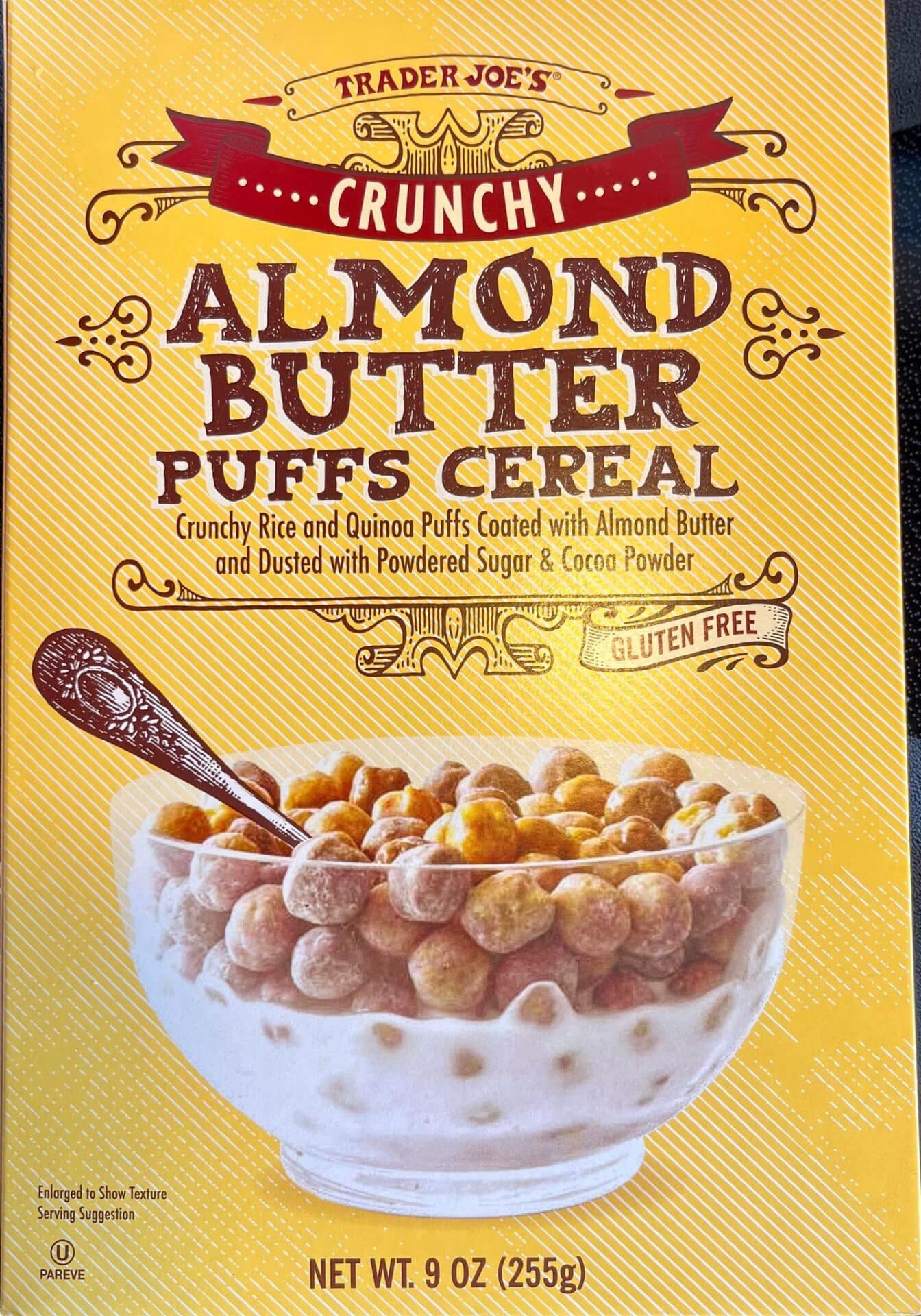 Box of Trader Joe’s Crunchy Almond Butter Puffs Cereal, featuring a bowl of round cereal puffs in milk, with product details such as gluten free and net weight 9 oz (255g) on a yellow background.