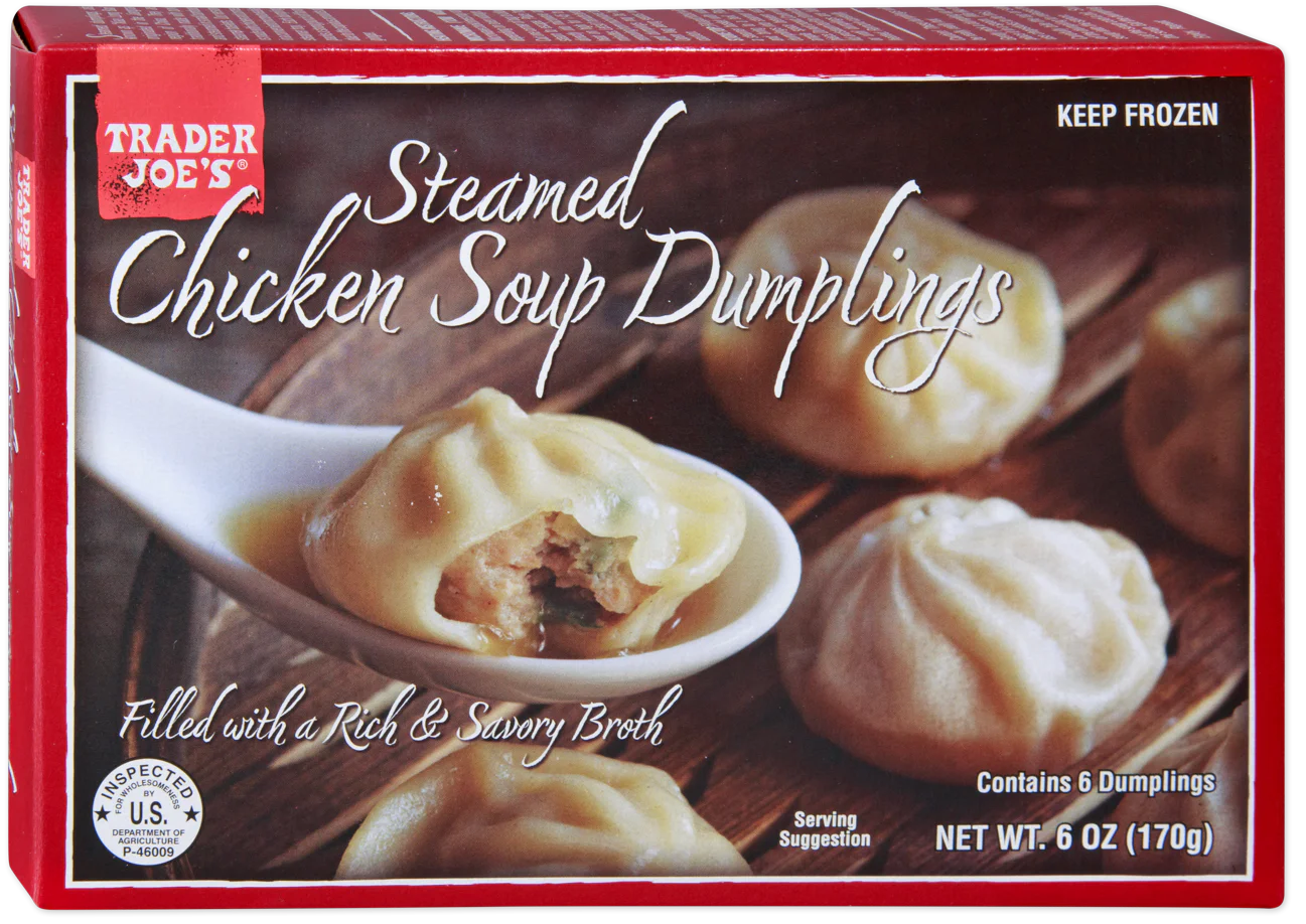 Box of Trader Joe’s Steamed Chicken Soup Dumplings, showing six dumplings on a plate with one cut open to reveal filling. The packaging highlights rich broth and contains 6 dumplings, net weight 6 oz (170g).