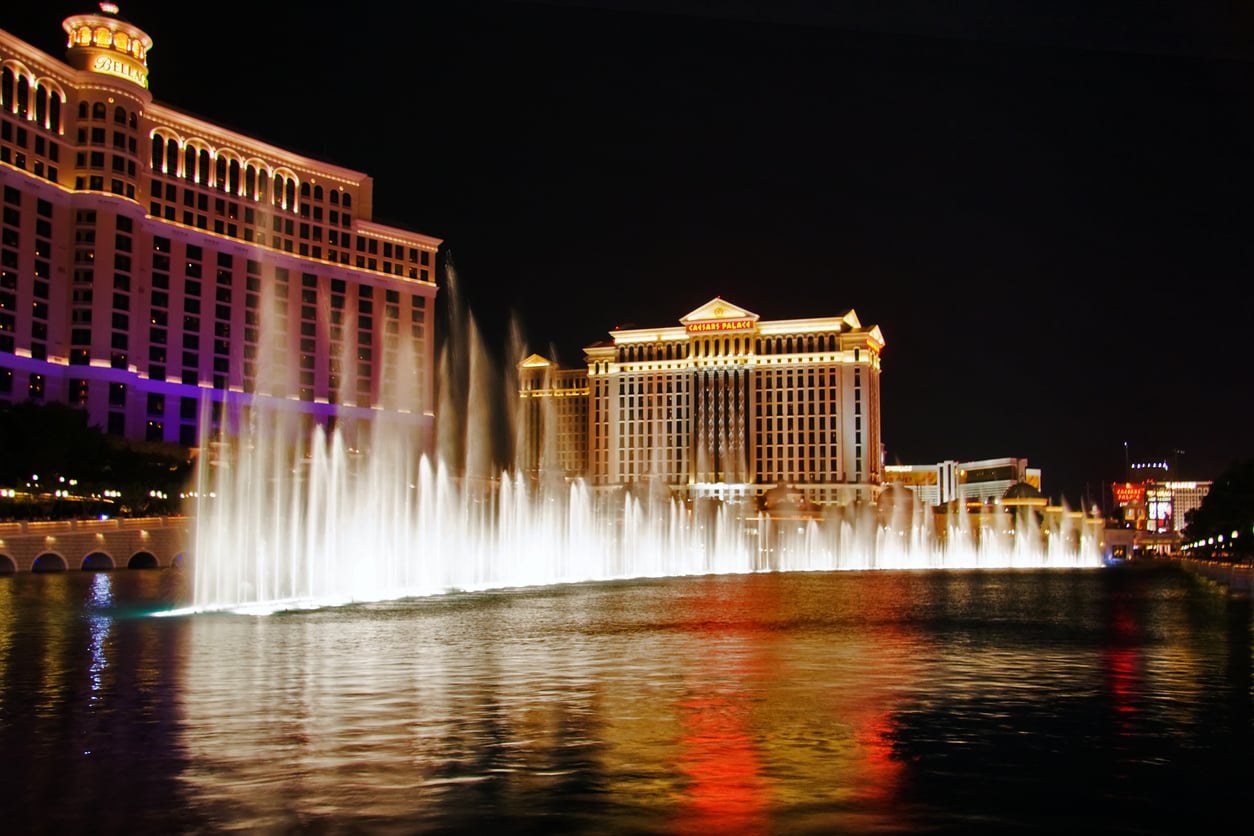 Night view of illuminated Las Vegas hotels with the Bellagio fountains spraying water high into the air, reflecting colorful lights—an iconic sight and one of the best free attractions for those seeking Las Vegas budget tips.