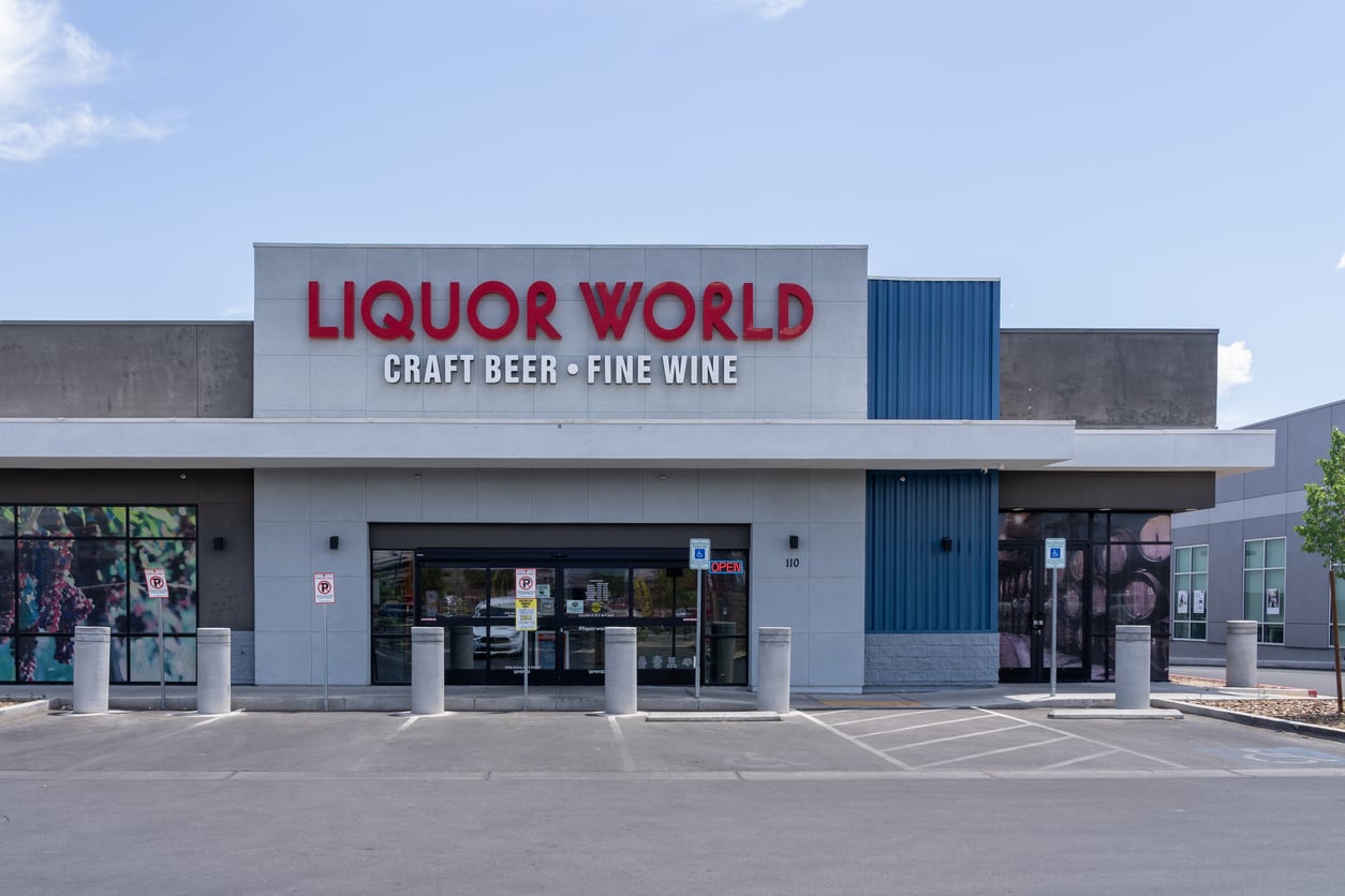 A liquor store named "Liquor World" with signs reading "Craft Beer" and "Fine Wine" above the entrance; accessible parking spaces are visible in front—perfect for those seeking Las Vegas budget tips on quality drinks.