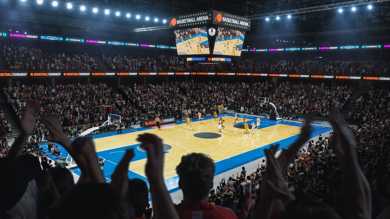 A crowded indoor basketball arena buzzes with excitement as fans—many sporting gear from products men skip buying—cheer with hands raised, while two teams battle on a brightly lit court beneath large “Basketball Arena” signage.