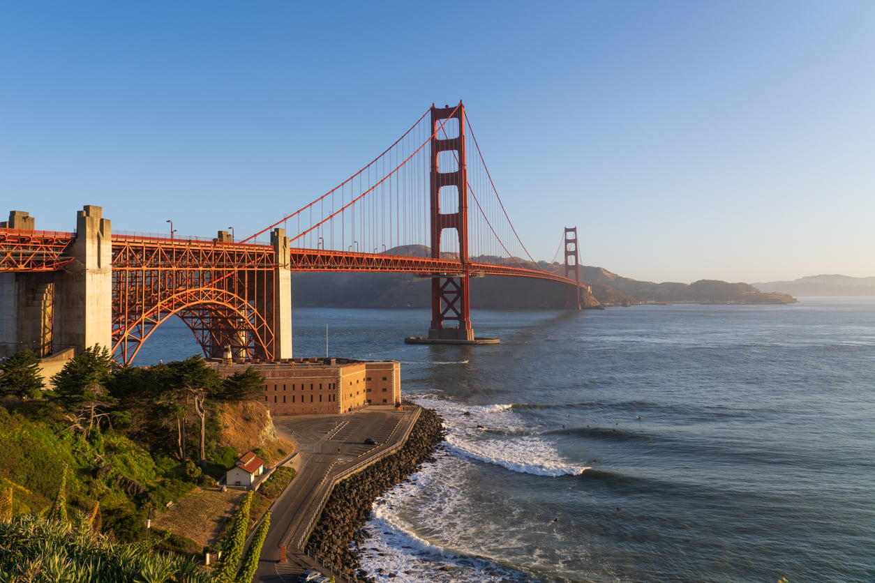 The Golden Gate Bridge in San Francisco is seen at sunrise, its iconic red towers spanning the bay—a stunning view that reminds some to leave credit card debt behind and chase new horizons beneath the clear blue sky.