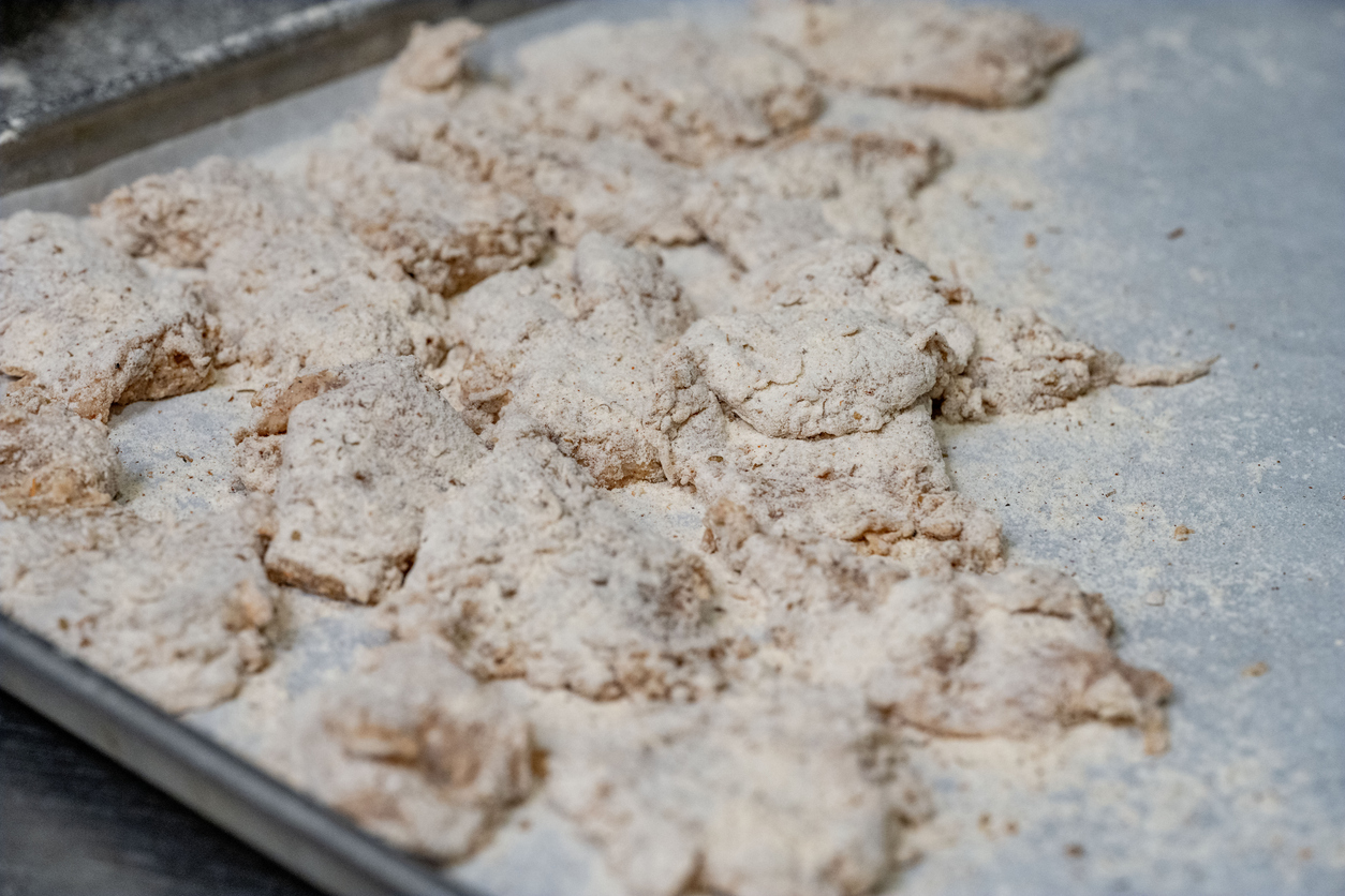 Fried chicken tricks. A baking tray filled with pieces of raw chicken coated in seasoned flour, ready to be cooked.