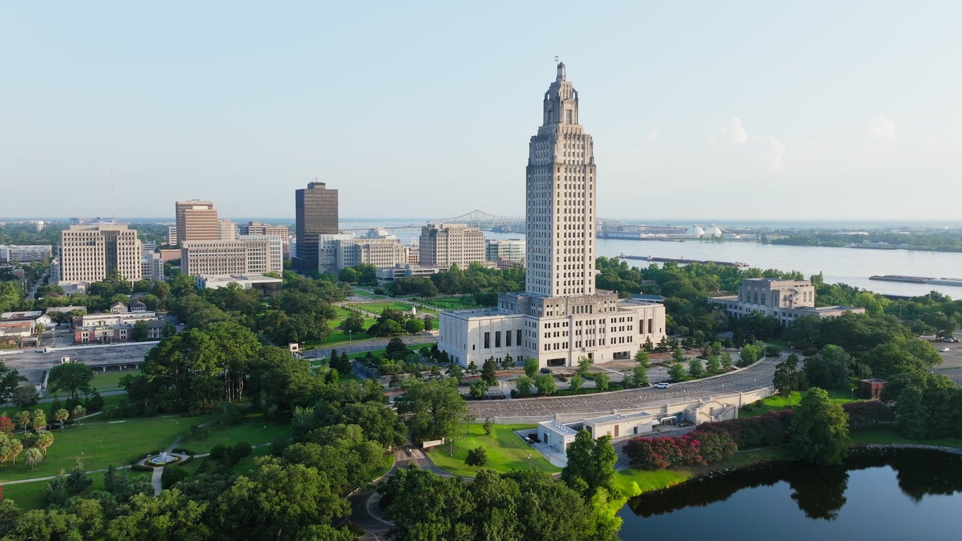 Aerial view of the Louisiana State Capitol building surrounded by green trees, with downtown Baton Rouge and the Mississippi River in the background—a striking contrast to the rising credit card debt many face today.