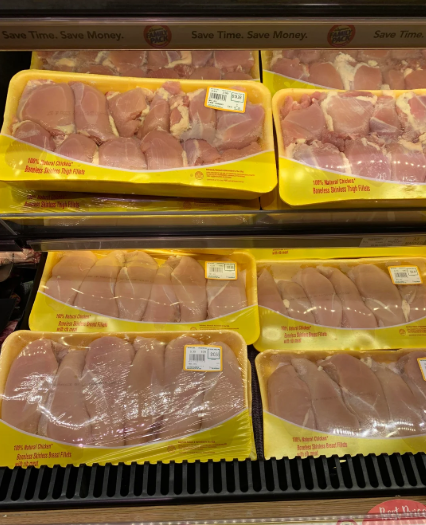 Several packages of raw, boneless, skinless chicken breasts are displayed on a grocery store shelf in yellow trays, wrapped in plastic with pricing labels—perfect for those looking to buy in bulk and save on meal prep.