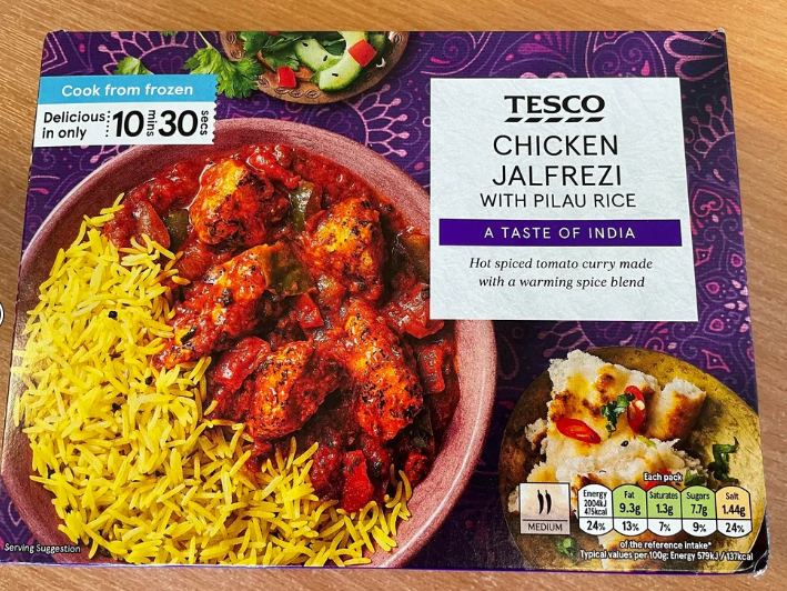 A Tesco ready meal box for Chicken Jalfrezi with pilau rice. The packaging shows a bowl of yellow rice and spicy tomato chicken curry, with nutritional info and the label "A Taste of India." Perfect to buy in bulk for quick, delicious meals.