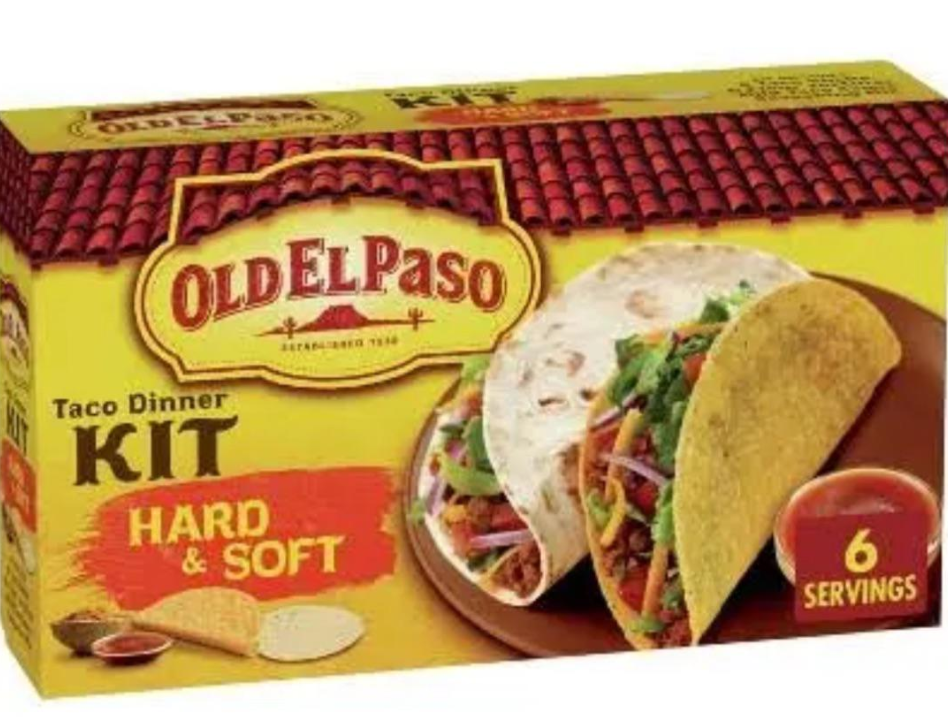 A yellow box of Old El Paso Taco Dinner Kit, labeled "Hard & Soft," features a soft tortilla and a hard taco shell filled with meat and vegetables—classic meals middle-class moms cooked. The box notes it contains 6 servings.