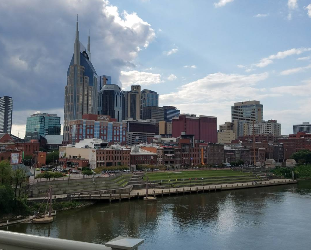 A view of downtown Nashville's skyline, featuring the iconic AT&T tower, modern and historic buildings, and a river in the foreground—reminding visitors that even cities as vibrant as Nashville aren't immune to challenges like credit card debt.