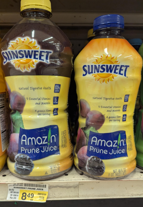 Two bottles of Sunsweet Amaz!n Prune Juice, a classic among foods that boomers still eat, are displayed on a store shelf—one with dark liquid, one lighter. Both bottles feature purple plums and yellow labeling, with price tags below.