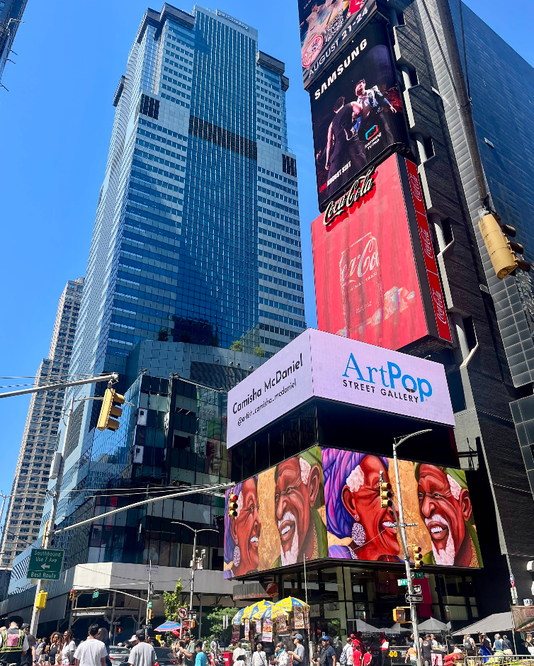 Skyscrapers and electronic billboards light up Times Square, one of New York City's top tourist attractions. Prominent signs include a Coca-Cola ad, ArtPop Street Gallery, and artwork by Camisha McDaniel. Crowds and street vendors fill the busy sidewalk below.