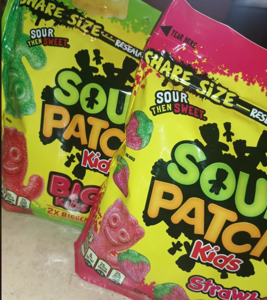 Two brightly colored bags of Sour Patch Kids, the best gummy candy, are shown. One bag is labeled "Big Kids" and the other "Strawberry." Both feature candy figures with "Sour Then Sweet" and "Share Size" text.