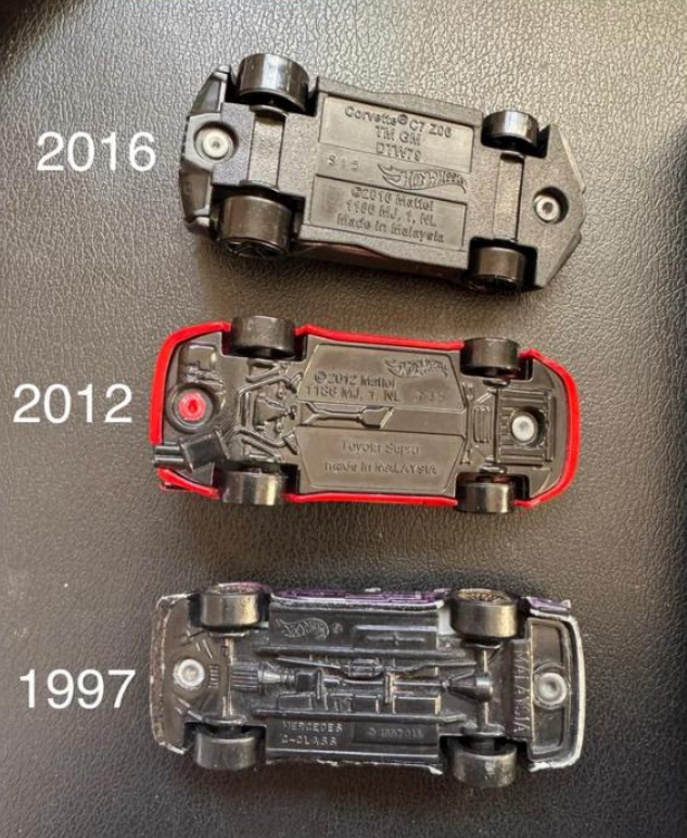 Three toy car undersides are shown on a dark surface, labeled by year: 2016 at the top, 2012 in the middle with a red edge, and 1997 at the bottom, each displaying different base designs and details.