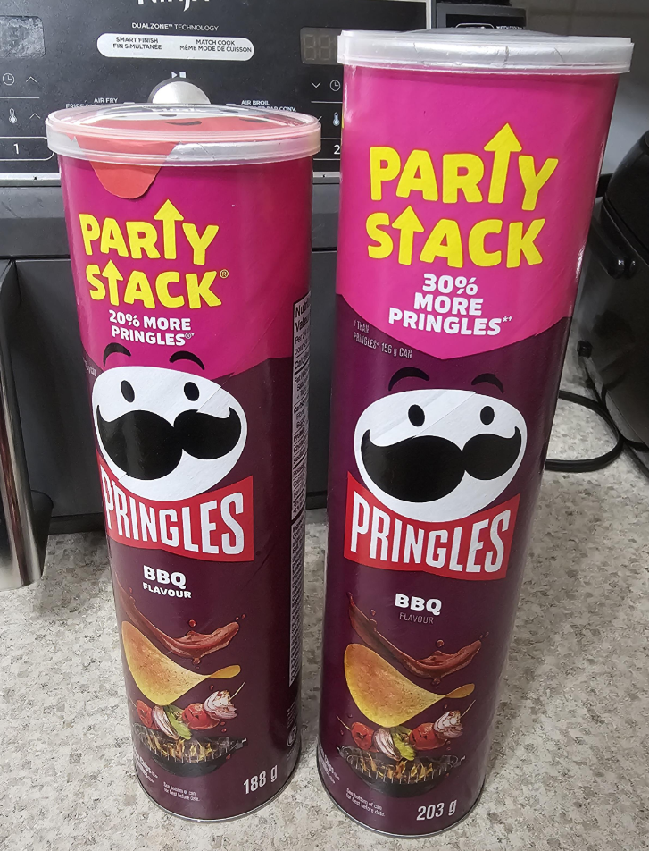 Two tall cans of Pringles BBQ flavor sit side by side on a counter. Both are labeled "Party Stack 30% more Pringles," but one weighs 188g and the other 203g. A stove and kitchen items are visible in the background.