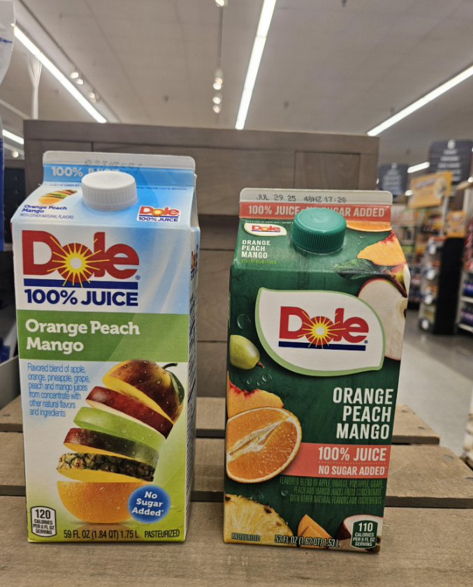 Two cartons of Dole Orange Peach Mango 100% Juice are displayed side by side on a wooden shelf in a grocery store. The cartons have different designs but contain the same flavor.