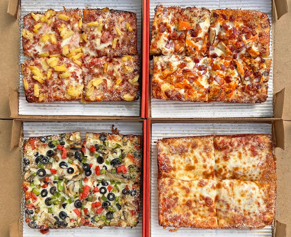 Four open pizza boxes from newer pizza chains, each featuring a rectangular pizza with different toppings: ham and pineapple, barbecue chicken, assorted vegetables with olives, and plain cheese—all arranged in a 2x2 grid.