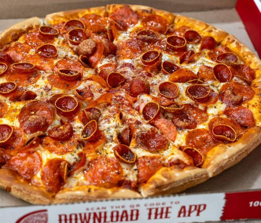 A freshly baked pepperoni pizza with a golden crust and melted cheese sits in an open pizza box, just like those from newer pizza chains, with "DOWNLOAD THE APP" printed on the box flap.