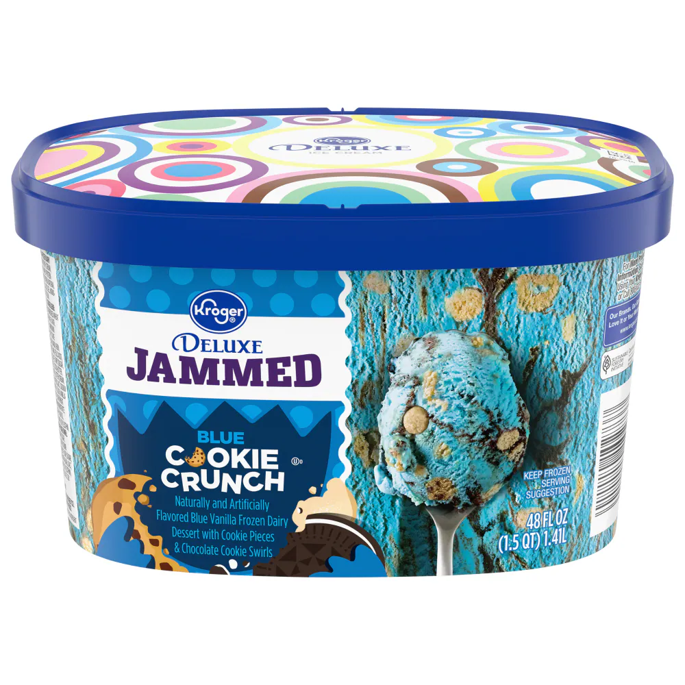 A tub of Kroger Deluxe Jammed Blue Cookie Crunch ice cream, featuring a blue vanilla frozen dairy dessert with cookie pieces and chocolate cookie swirls. The container is blue with colorful patterns and product information.