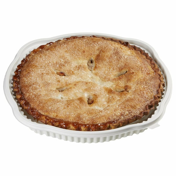 A whole baked pie with a golden, slightly sugared crust in a white, fluted disposable pie dish. The crust has small slits on top and some filling is visible around the edges.