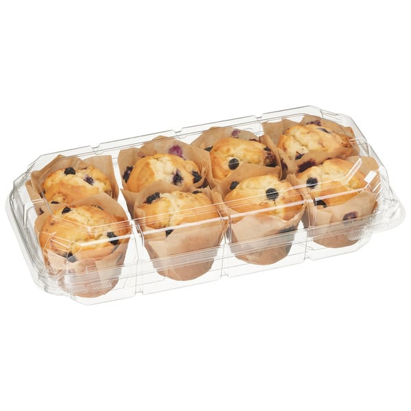 A clear plastic container holding eight blueberry muffins in brown paper wrappers, viewed from an angle.