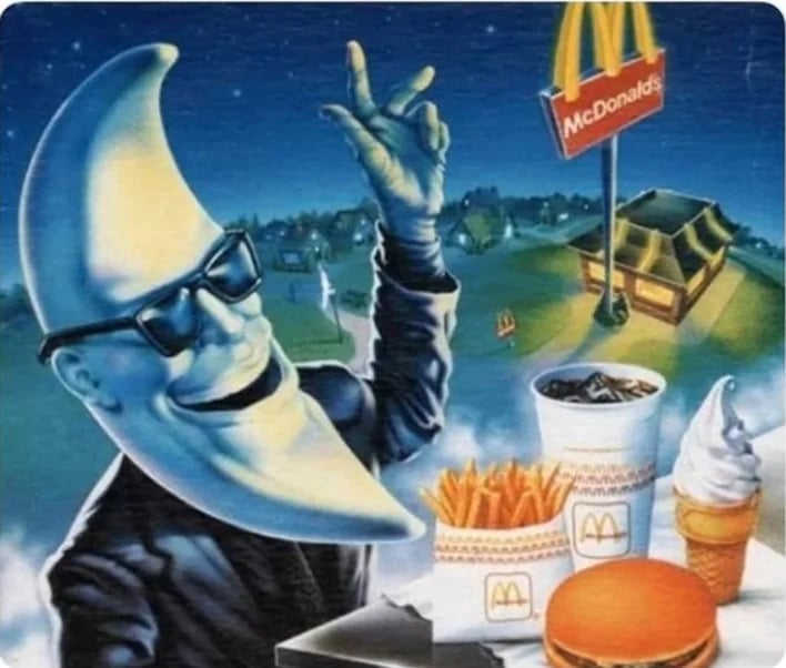 A person with a crescent moon head, wearing sunglasses and a suit, sits at a table with McDonald's food including fries, a drink, a burger, and ice cream, with a McDonald's restaurant in the background at night.