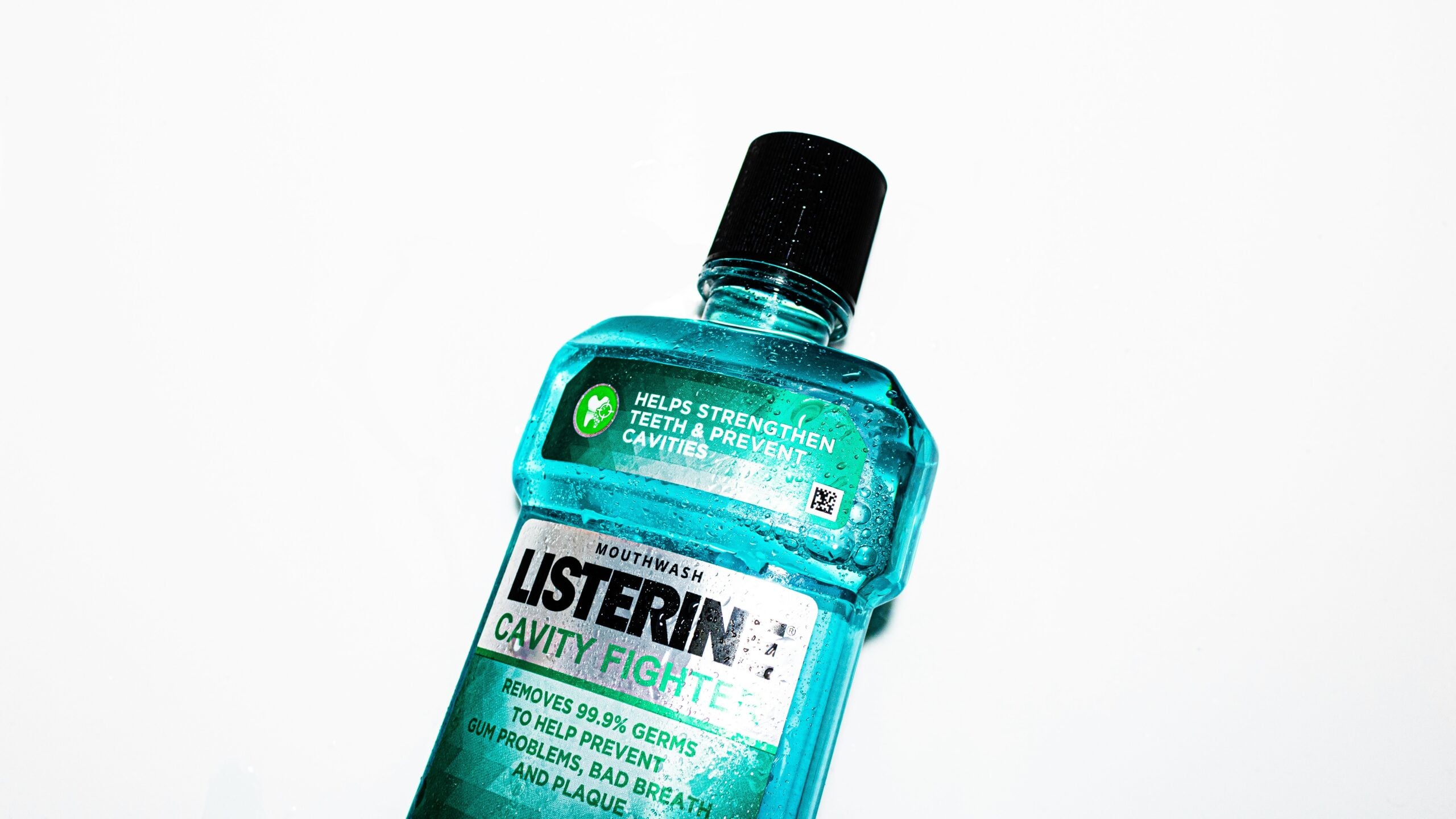 A teal bottle of Listerine mouthwash labeled "Cavity Fighter," shown on a white background. The label highlights that it helps strengthen teeth, prevents cavities, and kills 99.9% of germs.