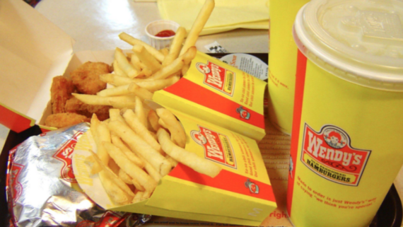 A nostalgic photo features two Wendy&rsquo;s containers of French fries, a wrapped burger, chicken nuggets, a cup of ketchup, and a large Wendy&rsquo;s soft drink cup neatly arranged on a tray.