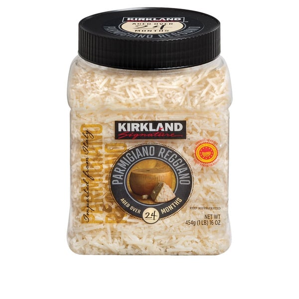 A clear plastic container of Kirkland Signature grated Parmigiano Reggiano cheese, labeled as aged over 24 months, with a black lid and a net weight of 454g (16oz).
