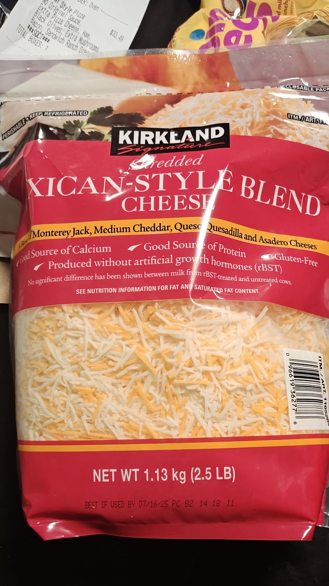 A bag of Kirkland shredded Mexican-style blend cheese, weighing 1.13 kg (2.5 lb), featuring Monterey Jack, cheddar, quesadilla, and asadero cheeses—the best shredded cheese choice for your favorite recipes. The bag sits on a kitchen counter.