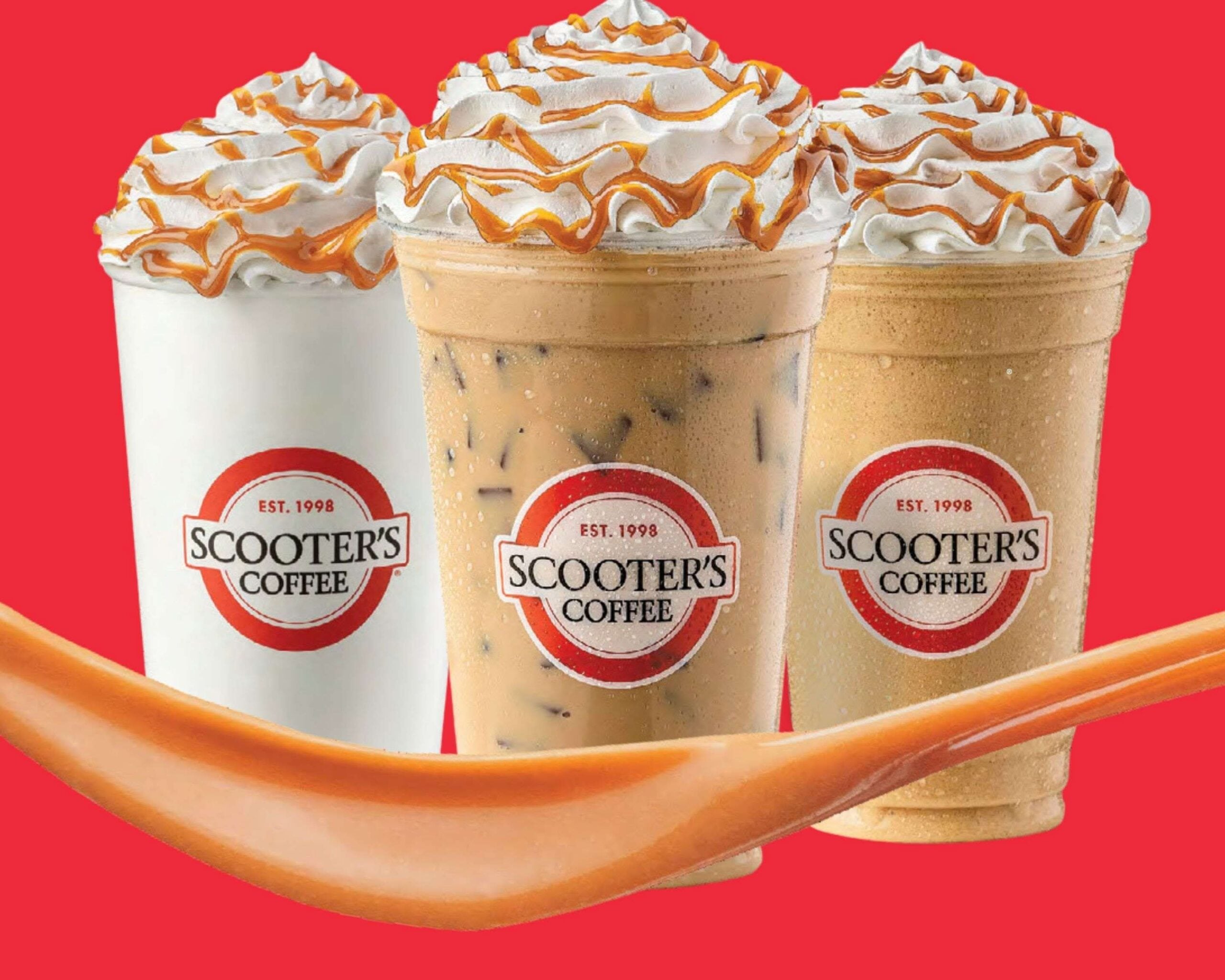 Three Scooter’s Coffee drinks—one hot, one iced, and one blended—topped with whipped cream and caramel drizzle sit in front of a red background, capturing the cozy vibe found in today’s modern coffee houses. An orange spoon rests in the foreground.